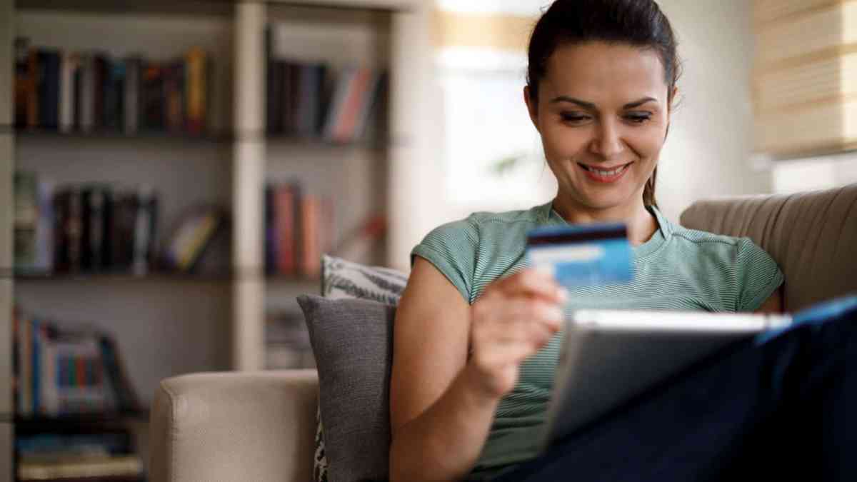 Eine Frau sitzt mit ihrer Kreditkarte vor dem Laptop.