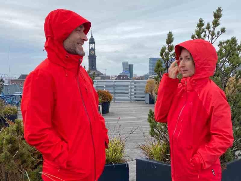 Ein Mann und eine Frau in roten Regenjacken vor grauem Himmel