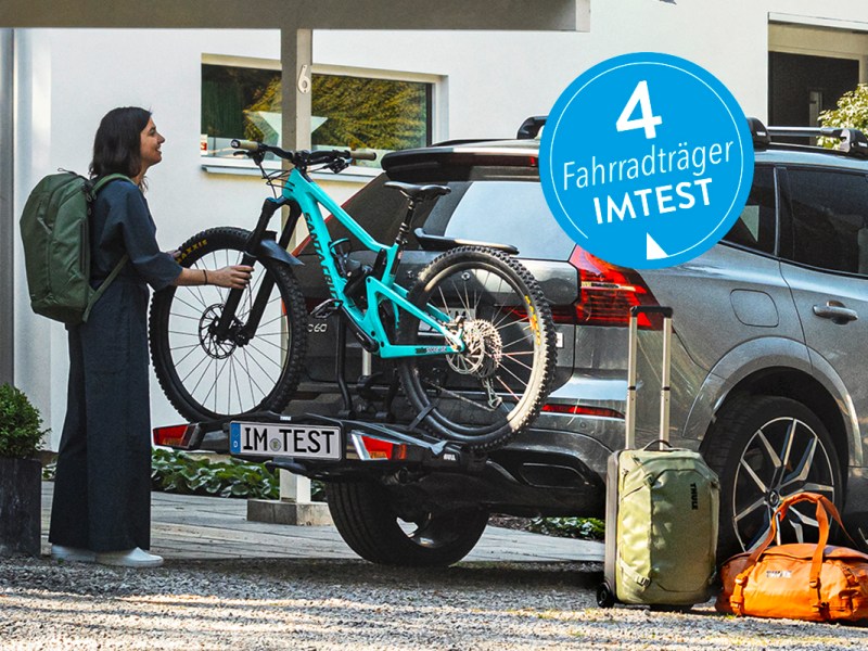 Eine Frau steht an einem AUto mit Fahrradträger