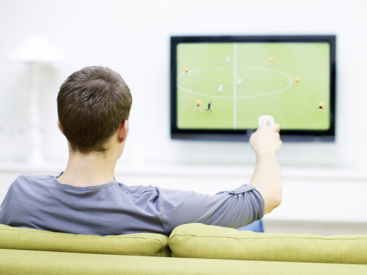 Ein Mann sitzt vor dem TV und schaut Fußball