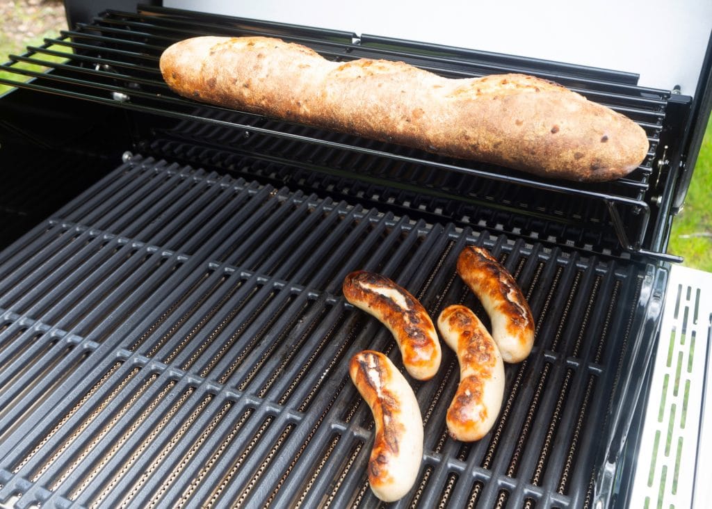 Bratwürste und Brot werden auf Grill gegart