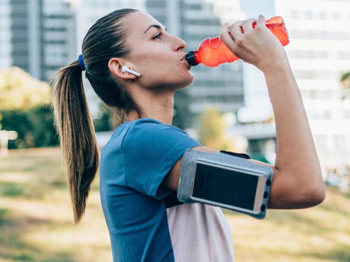 Joggerin trinkt aus einer Flasche.