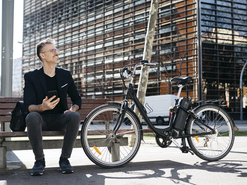 Mann sitzt auf Bank mit E-Bike