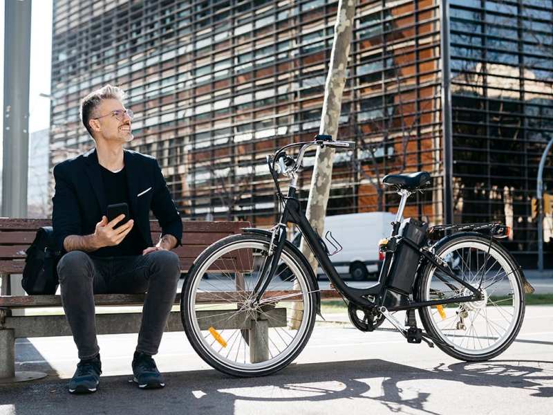 Mann sitzt auf Bank mit E-Bike