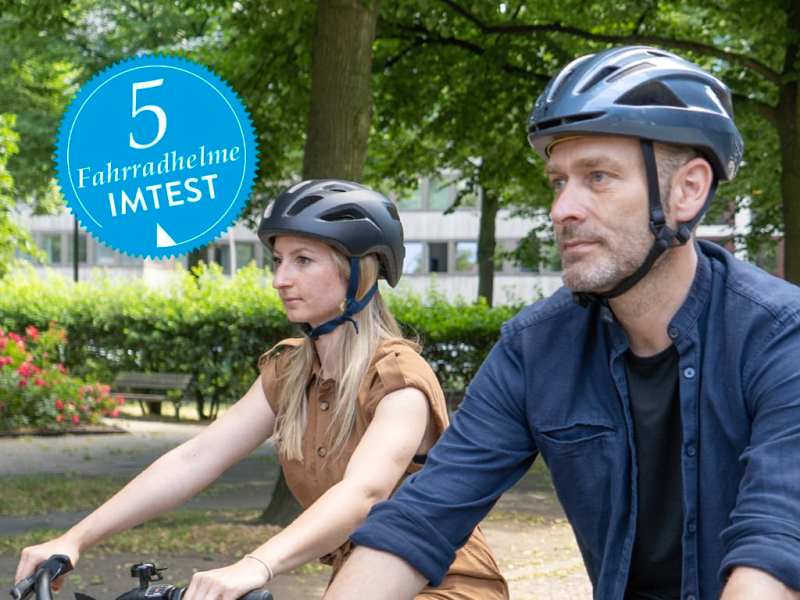 Woman and man in bicycle helmets cycling.