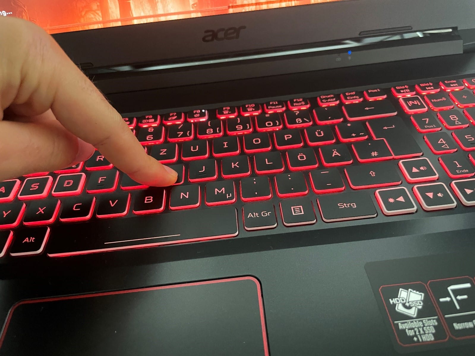 Tastatur Notebook leuchtet rot. Finger drückt Taste