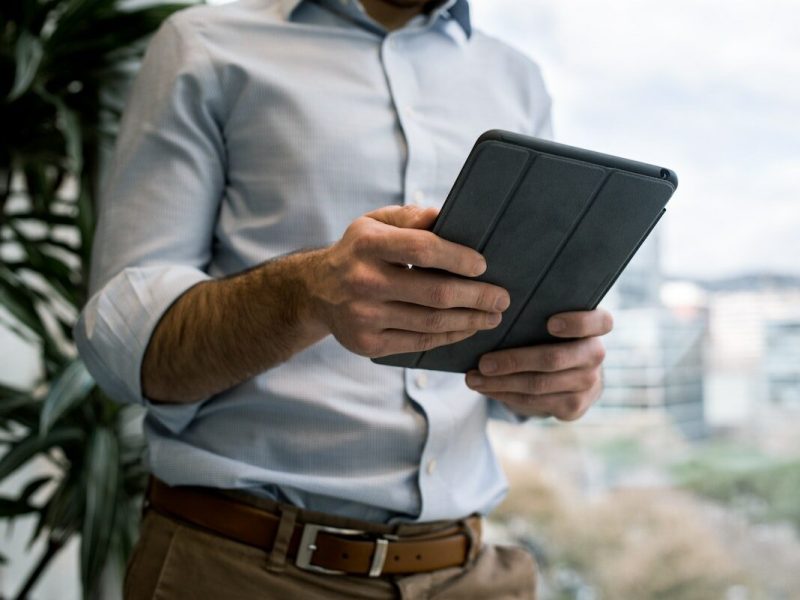 Ein Mann hält ein Tablet in der Hand.