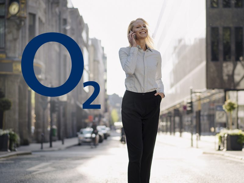 Business Frau telefonierend auf offener, heller Straße, daneben das Logo von o2