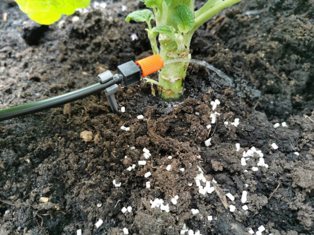 Wasserschlauch mit orangener Düse bewässert pflanze