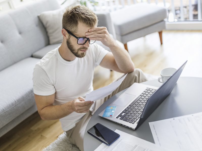 Mann arbeitet mit Notebook im Wohnzimmer