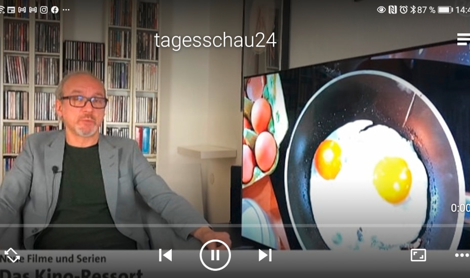 Screeshot von Handy mit TV Bild, zeigt Mann im grauen Sakko und Einblendung von Bratpfanne mit Spiegelei