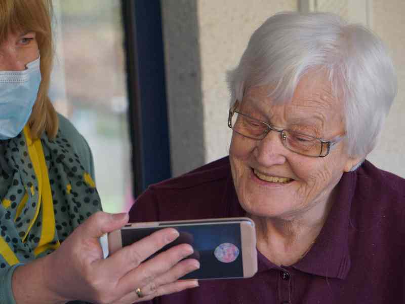 Eine ältere Dame schaut auf ein Smartphone.