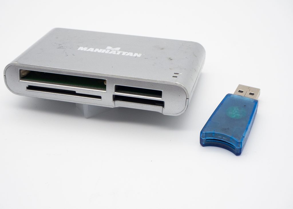 Blauer USB Stick neben silbernem Gerät auf weißem Grund