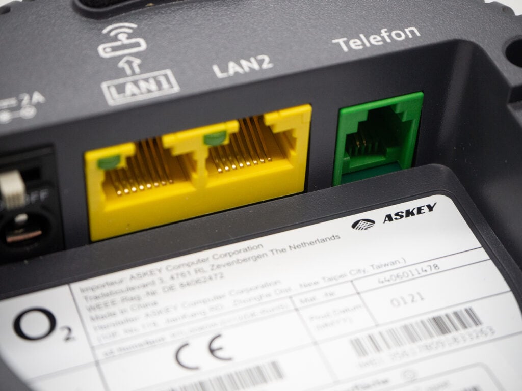 Detailaufnahme graues Gerät mit zwei gelben und einem grünen Anschluss für LAN und Telefon