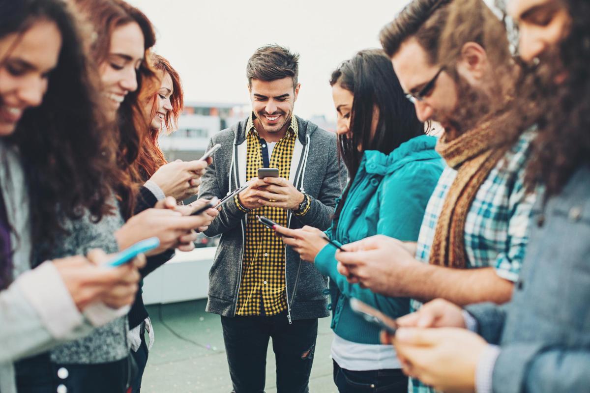 Junge Leute stehen zusammen und bedienen Smartphones
