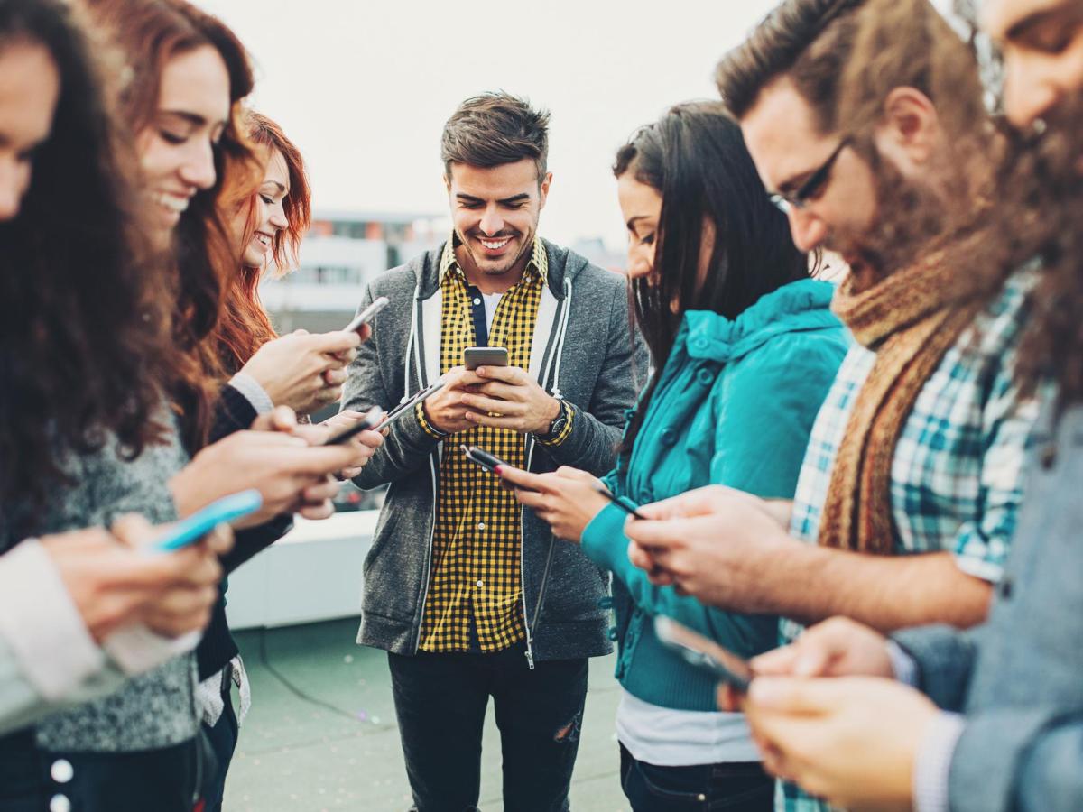 Junge Leute stehen zusammen und bedienen Smartphones