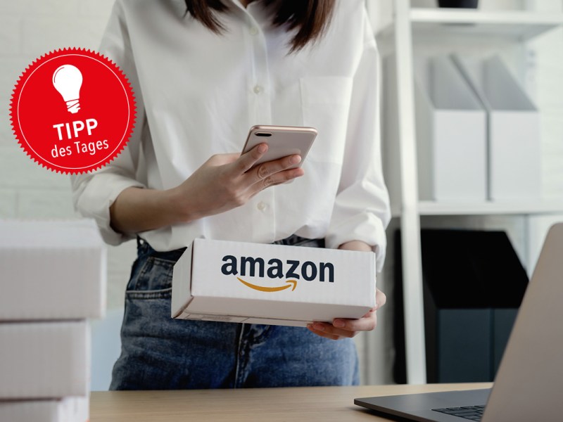 Frau mit Amazon-Paket und Smartphone in der Hand.