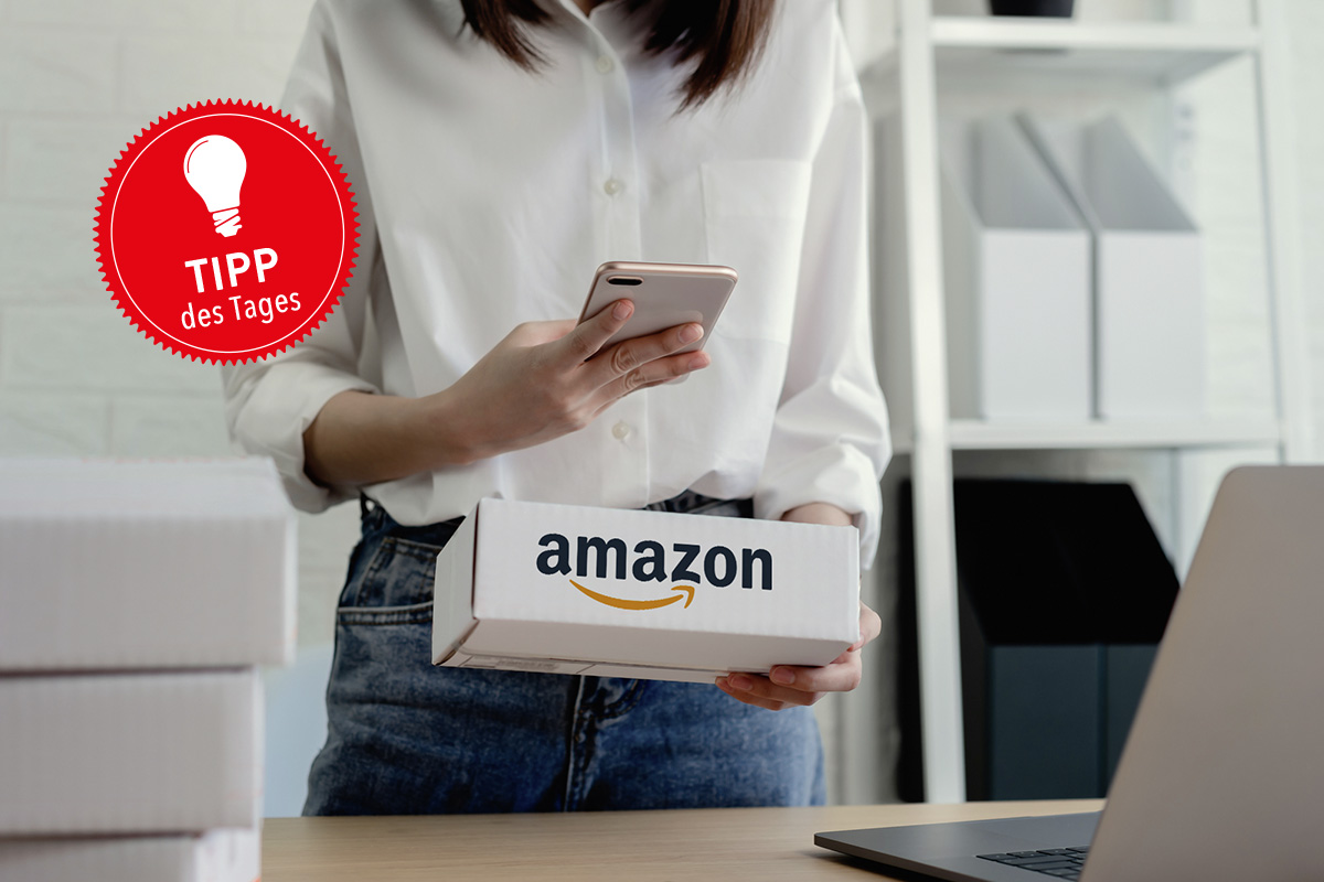 Frau mit Amazon-Paket und Smartphone in der Hand.