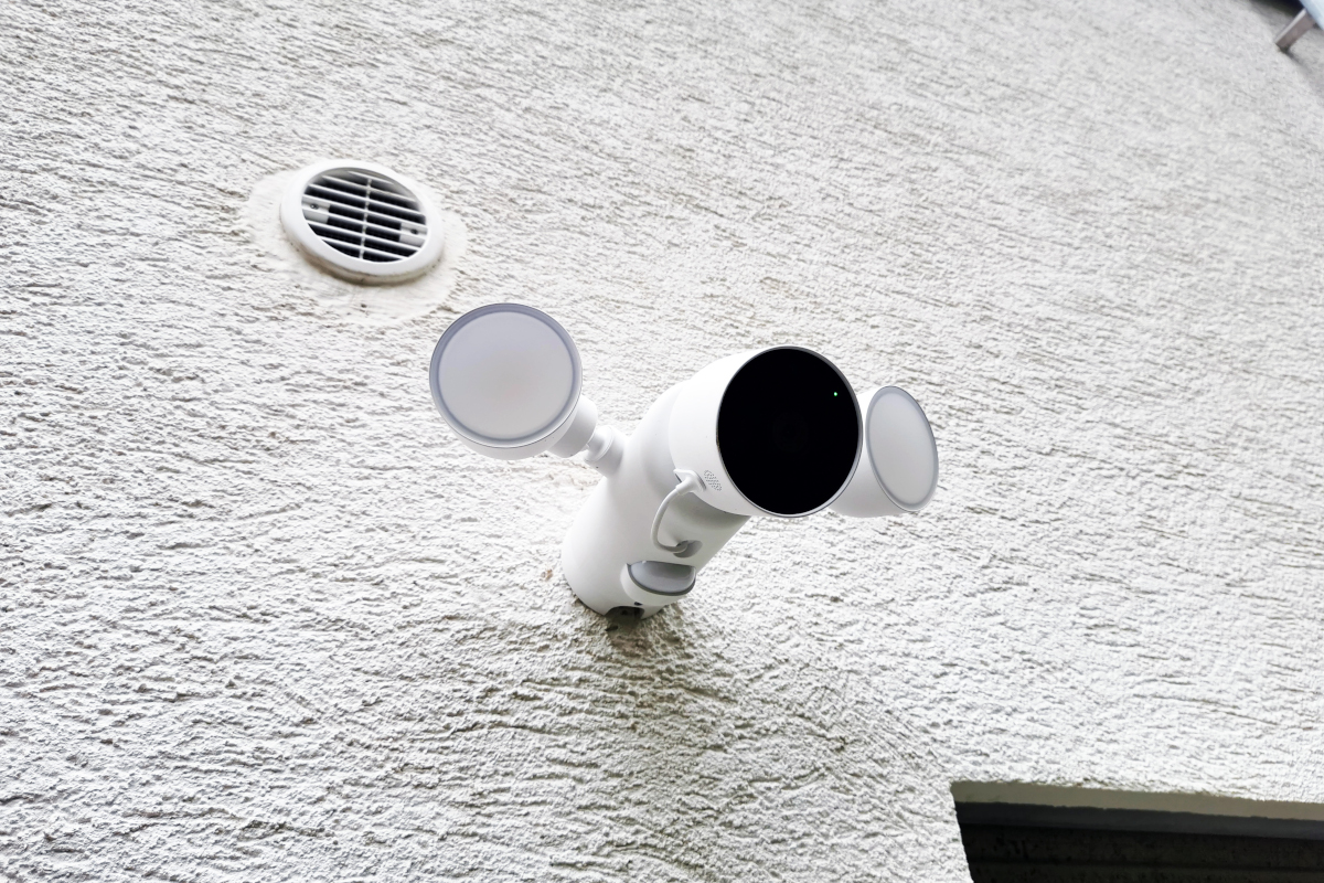 Weiße Überwachungskamera hängt an weiß verputzter Wand