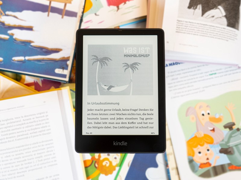 Schwarzer E-Book-Reader mit geöffneter seite vor verschiedenen Texten mit bunten Bildern