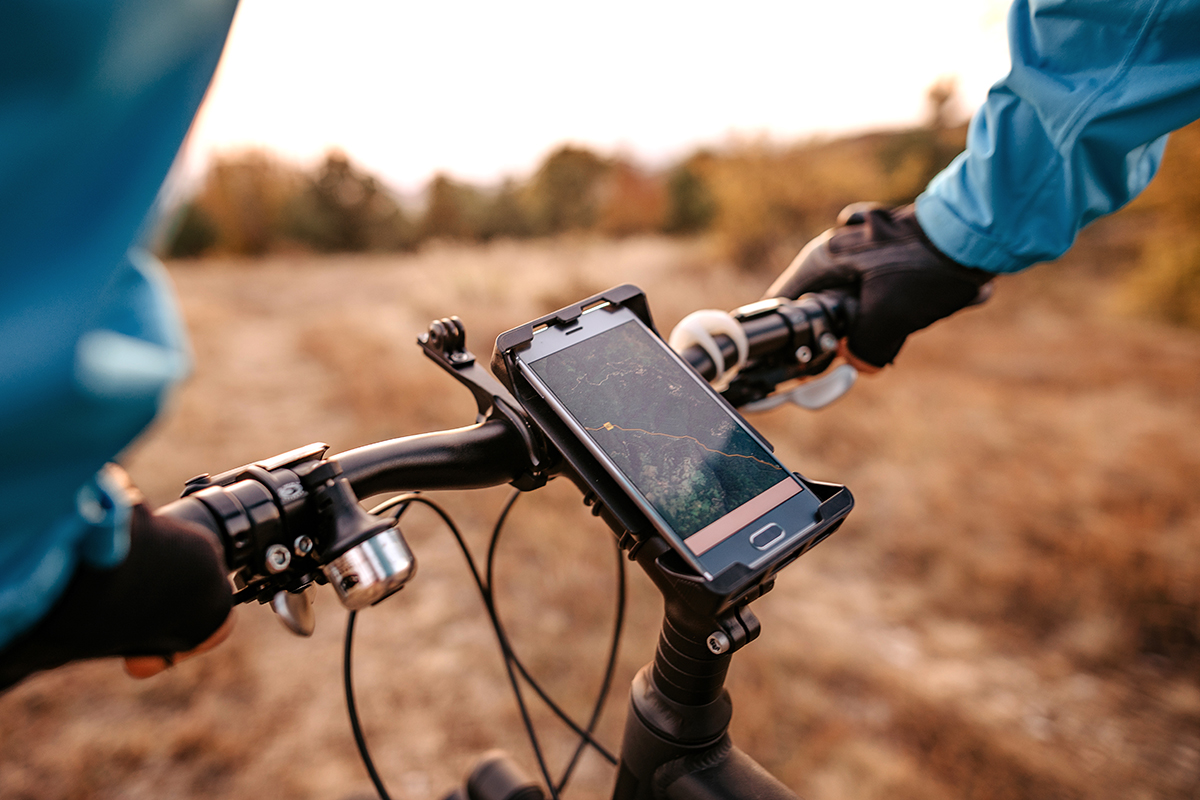 E-Bike-Fahrer im Gelände mit Smartphone für Navigation.