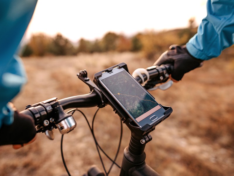 E-Bike-Fahrer im Gelände mit Smartphone für Navigation.