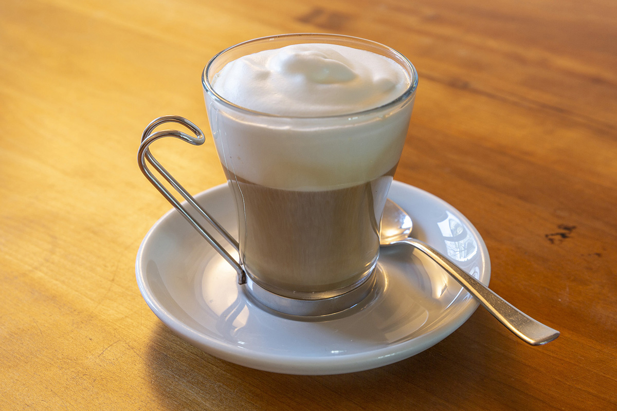 Cappuccino in Becher auf Holztisch mit festem Schaum