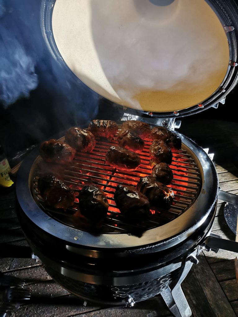 Schwarzer Grill mit geöffnetem Deckel und belegtem Rost