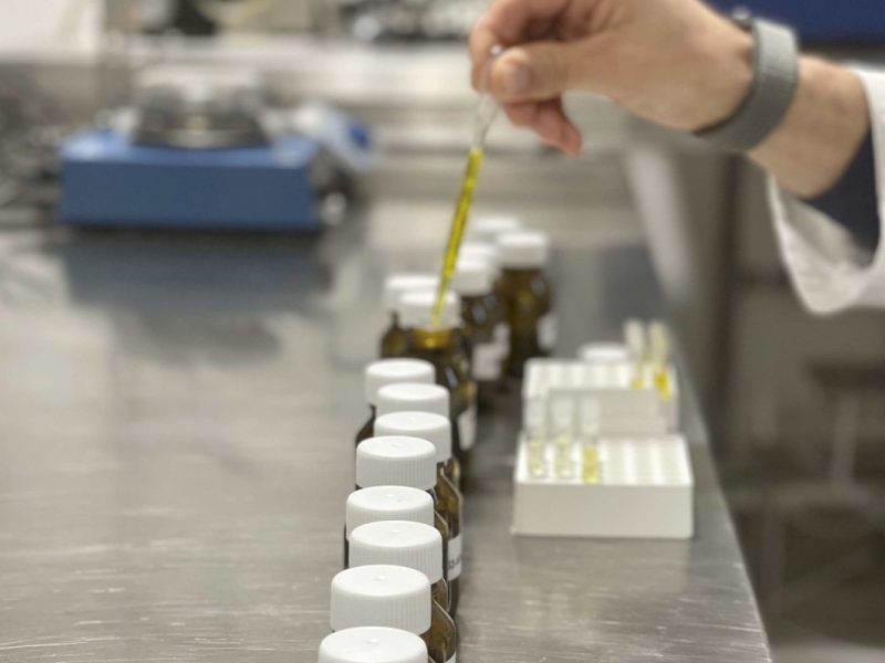 Ein Labormitarbeiter entnimmt Proben mti einer Pipette.