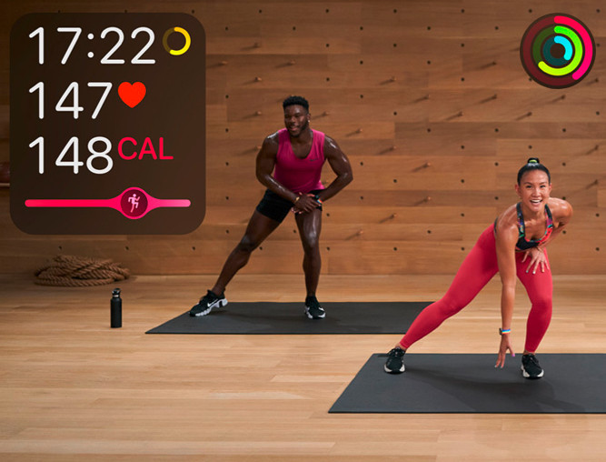 Zwei Trainer auf Fitnessmatten dehnen sich, links sind Herzfrequenz und mehr Infos rund um Gesundheit und Fitness eingeblendet