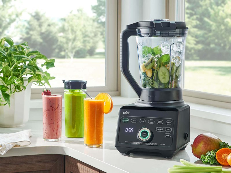 Fensterbank mit gefülltem Standmixer und Gläsern mit Smoothies daneben