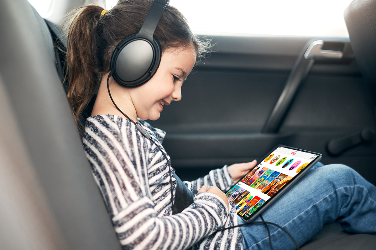 Mädchen sitzt im Auto und guckt Netflix Kids auf Tablet.
