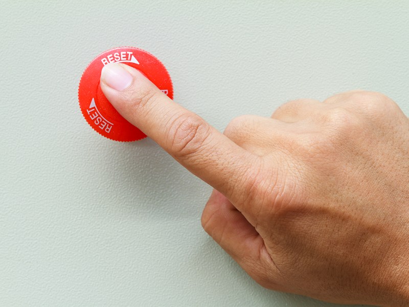 Finger drückt roten Reset-Knopf