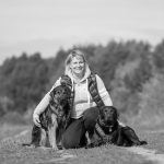 Frau sitzt mit Hunden in der Natur, schwarz weiß