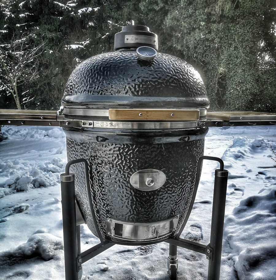 Schwarzer ovaler Standgrill im winterlichen Garten