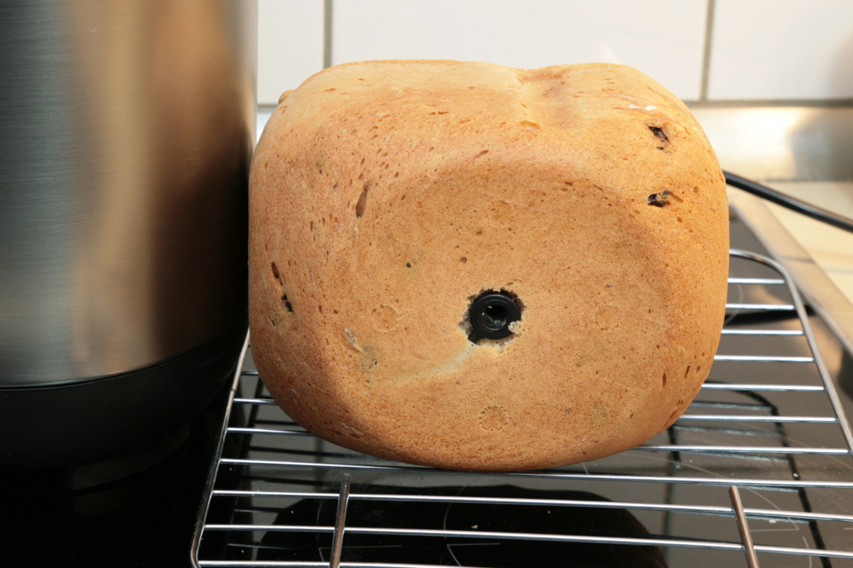 Ovales helles Brot mit schwarzem Loch in der Mitte von vorne auf Rost