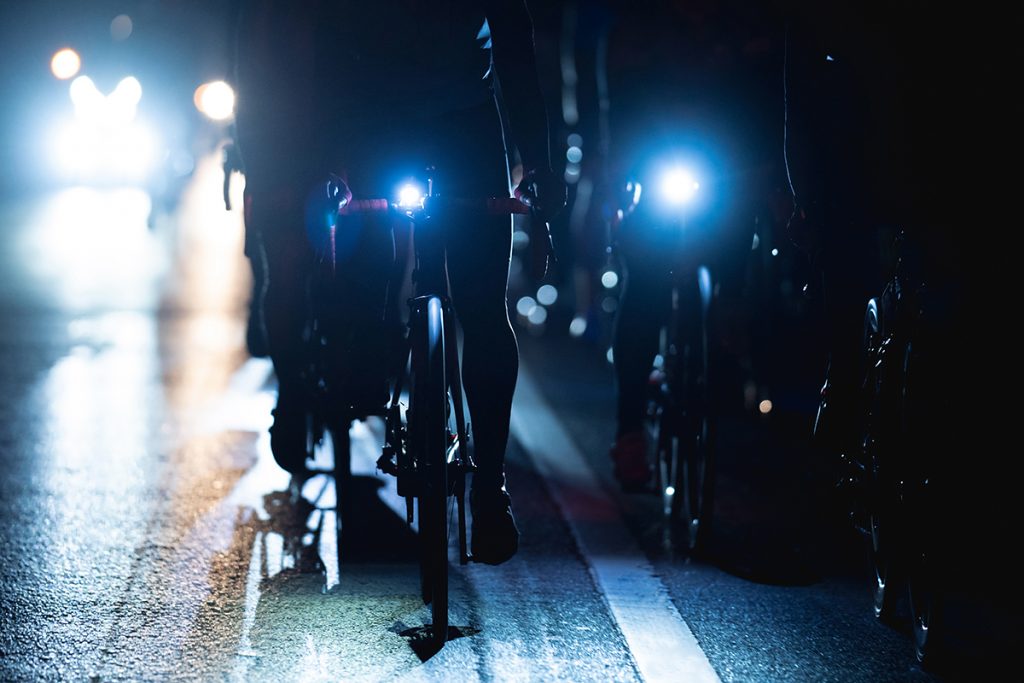 Eine Gruppe Fahrradfahrer bei Dunkelheit mit eingeschaltetem Fahrradlicht.