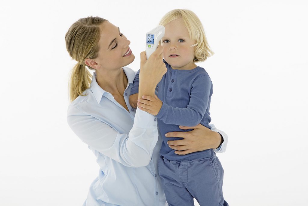 Frau misst mit Infrarot-Thermometer Fieber bei einem Kind 
