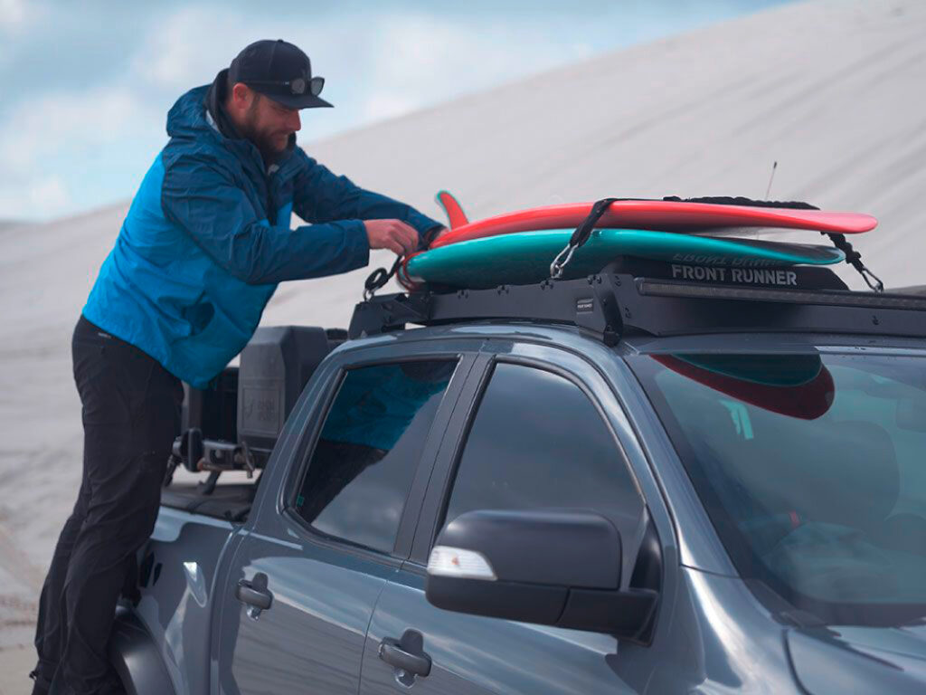Mann befestigt Surfboards auf Autodach