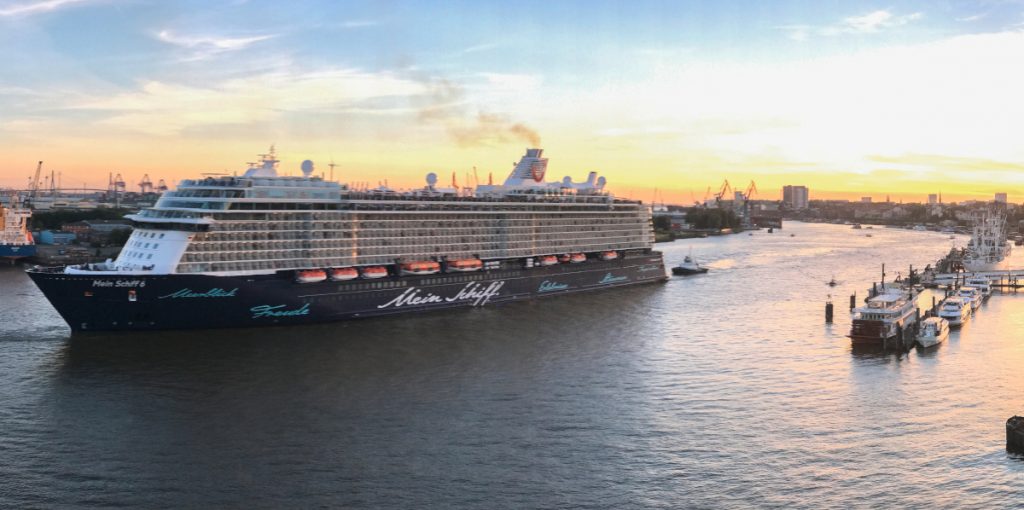 Foto zeigt auslaufendes Kreuzfahrtschiff in Hamburger Hafen von der Seite bei Sonnenuntergang
