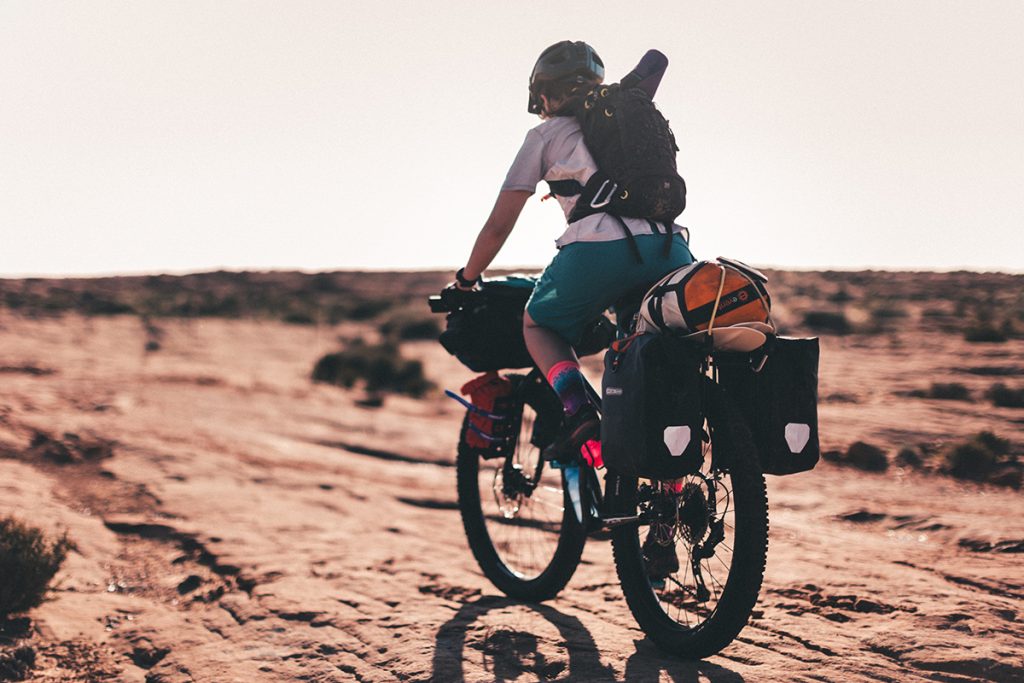 E-Bike-Fahrer mit bepackten Rad auf staubiger Piste unterwegs