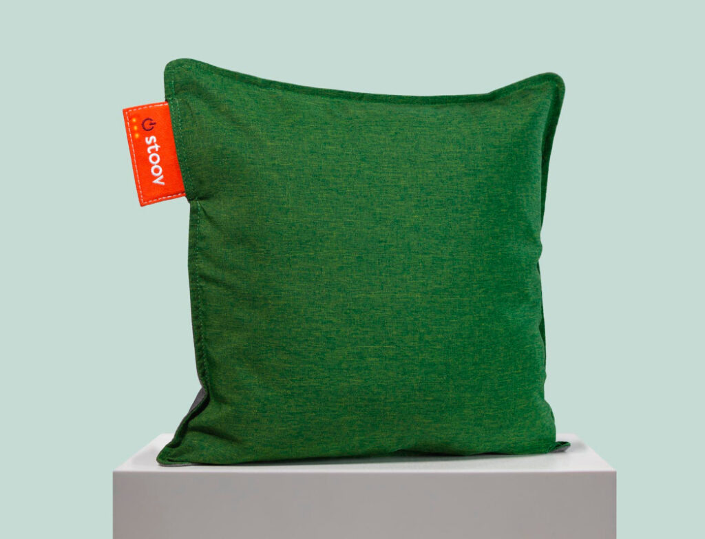 Grünes rechteckiges aufgestelltes Kissen vor hellgrünem Hintergrund