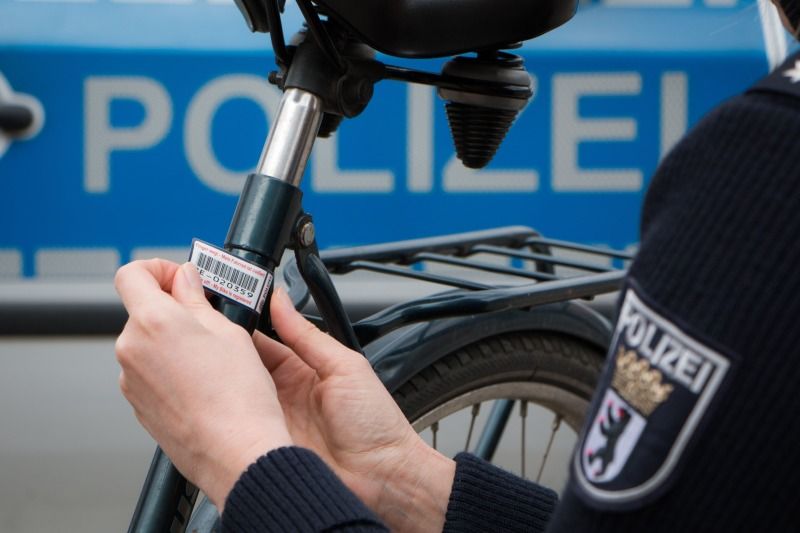Ein Fahrrad wird von einem Polizei-Beamten mit einem Code gekennzeichnet.
