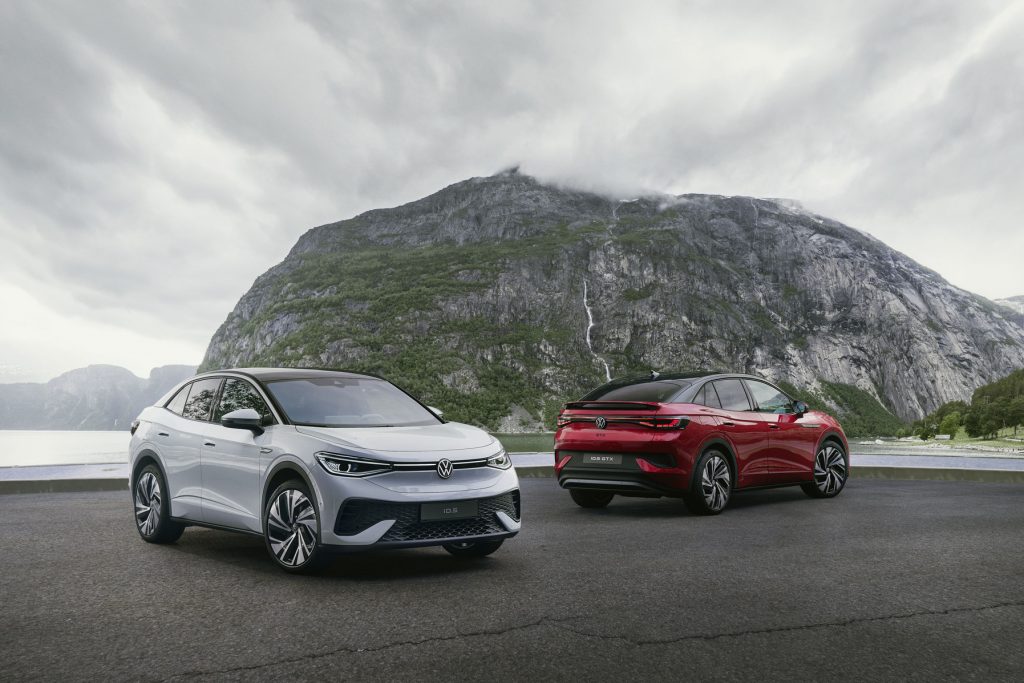 Ein silbernes und ein rotes Auto nebeneinander von verschiedenen Seiten vor Bergkulisse