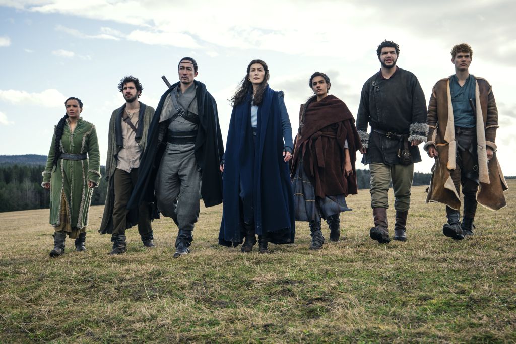 Sieben Personen in Mittelalter-Kleidung gehen auf Feld in Reihe