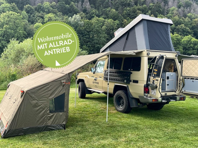 Wohnmobile für Abenteurer: Land Cruiser mit aufgestelltem Hochdach und Beistellzelt vor Waldlandschaft.
