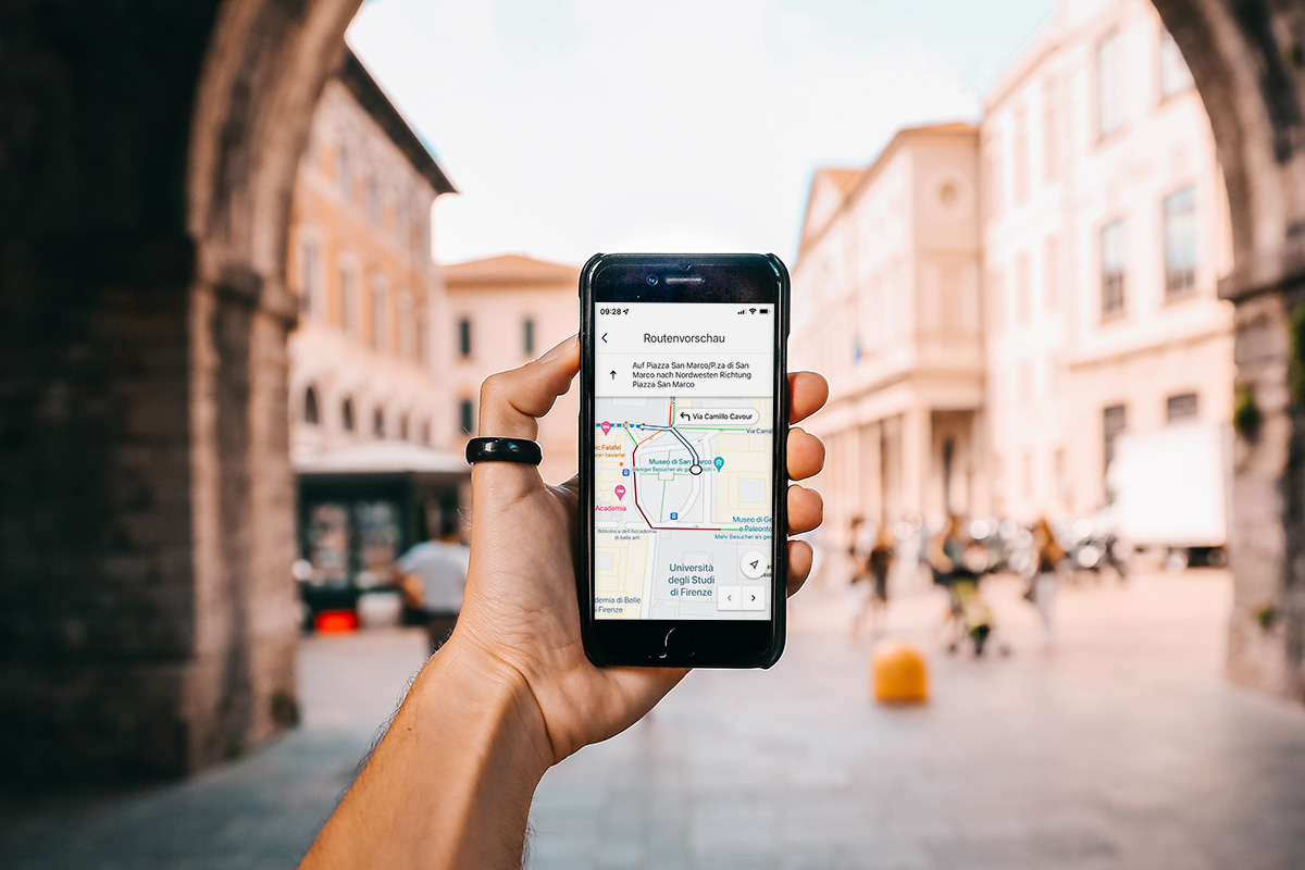 Ein Tourist hält ein Handy, auf dem eine GoogleMaps-Route zu sehen ist.