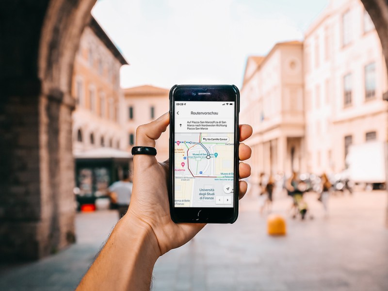 Ein Tourist hält ein Handy, auf dem eine GoogleMaps-Route zu sehen ist.
