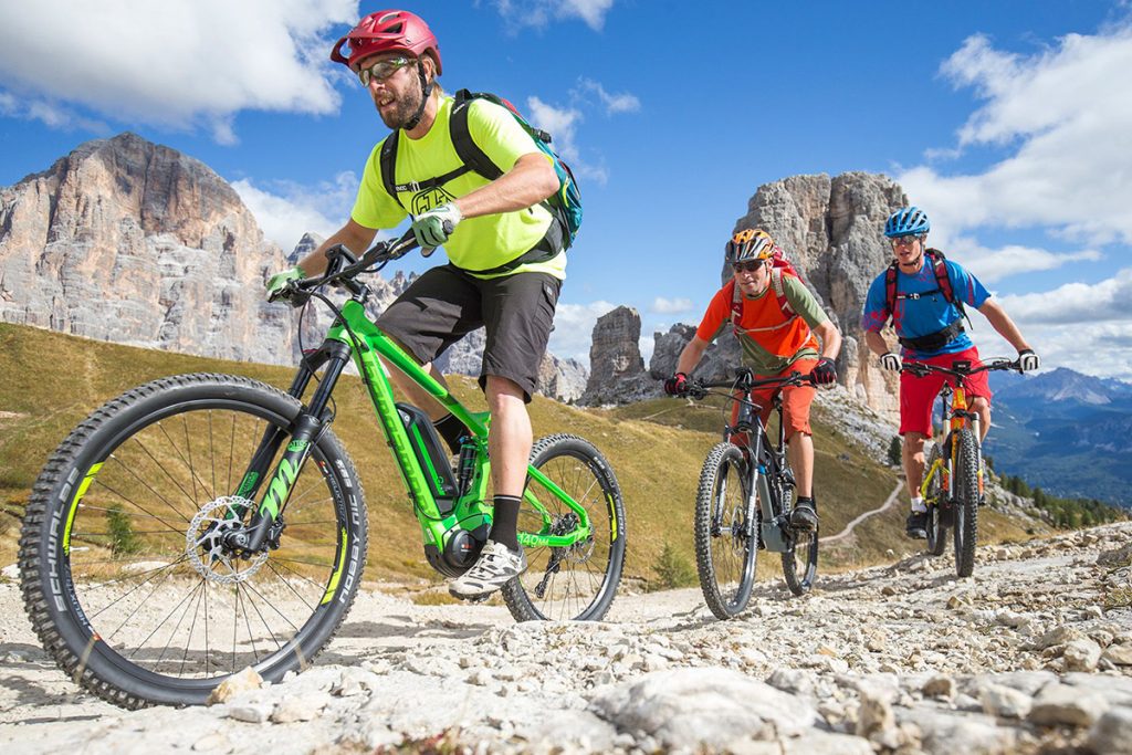 Drei E-Mountainbike-Fahre mit ihren Rädern im Gebirge unterwegs