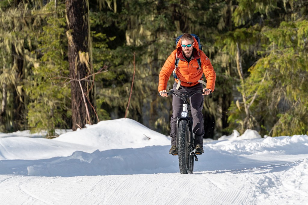 Mann fährt auf E-Bike durch verschneite Landschaft